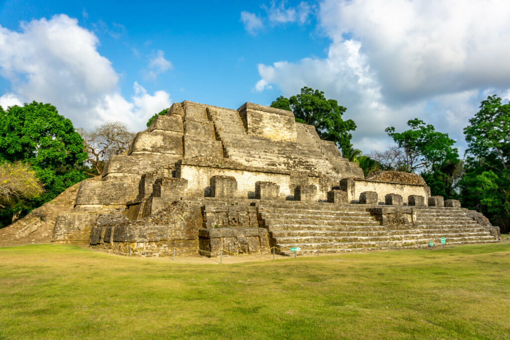 Ancient ruins of a South American pyramid style built in the forrest, sunny day with clouds looming in the sky.