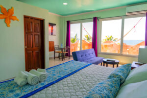 Hotel room with king size bed and view of the ocean from the window.