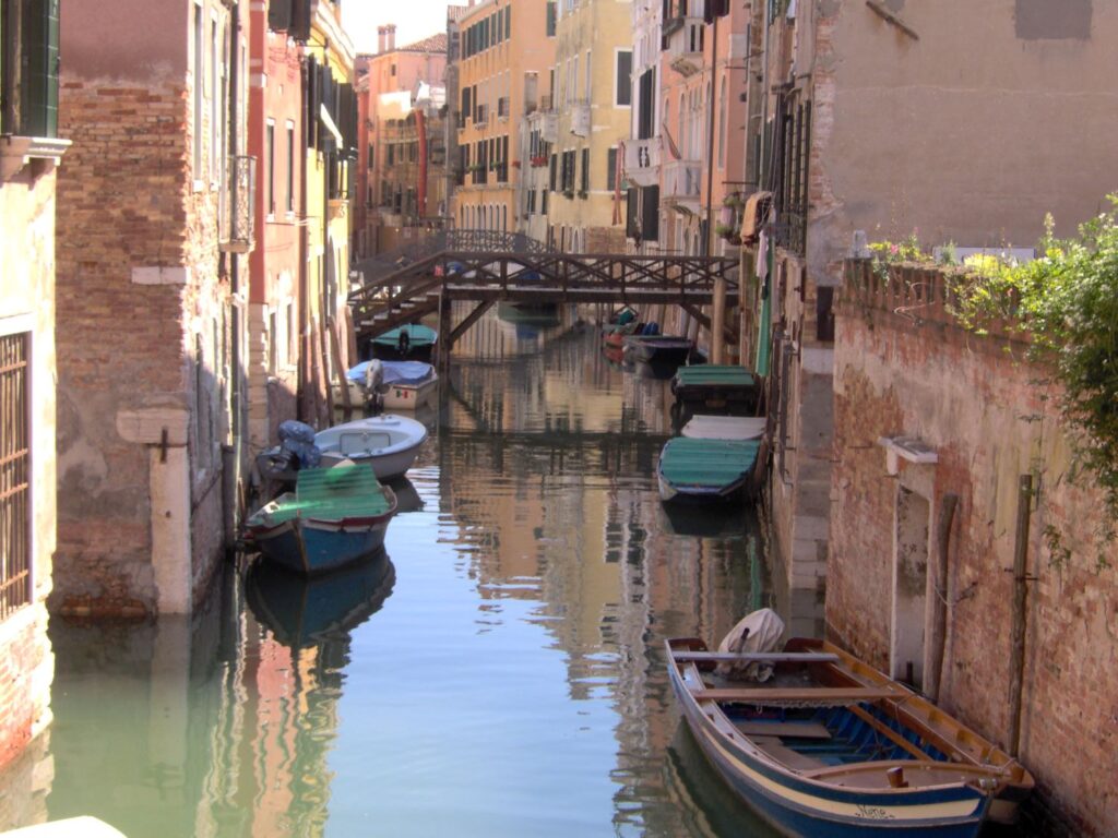 Venetian Canal photo of a water canal in Venice with gondolas parked along the buildings.